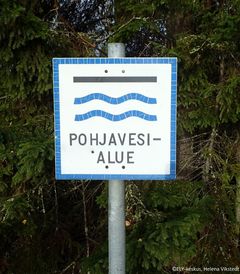 Metsä taustalla, ja kyltti missä lukee "Pohjavesialue".