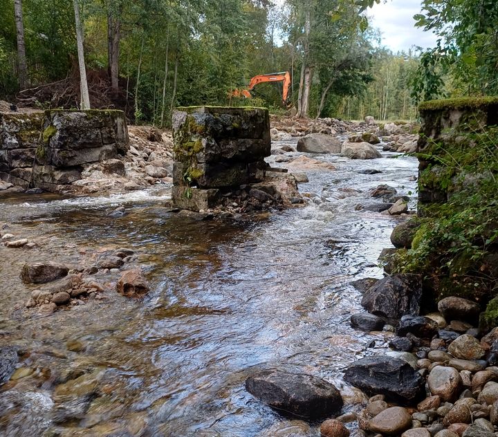Vanhaa patoa puretaan kaivinkoneella vesiuomassa.