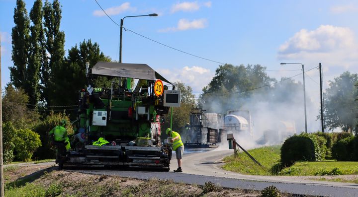 Tieasfalttityö käynnissä maaseudulla, jossa työmiehet ja -koneita.
