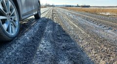 Bil parkerad vid lerig och uppkörd landsväg.