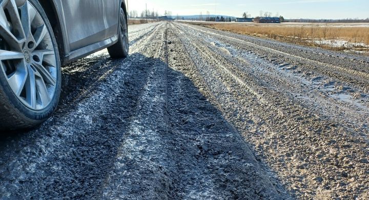 Bil parkerad vid lerig och uppkörd landsväg.