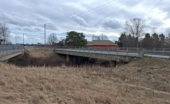 Silta, joka ylittää kuivuneen joenuoman, taustalla pilvinen taivas.