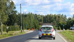 Auto ajaa maantiellä, ja kyltissä lukee "Seuraa minua".