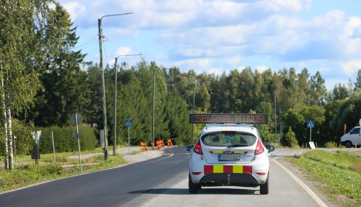 Auto ajaa maantiellä, ja kyltissä lukee "Seuraa minua".