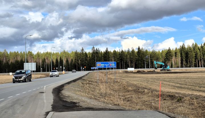 Tiehankkeeseen liittyvä työmaa, taustalla autoja ajamassa isolla tiellä ja metsää horisontissa.