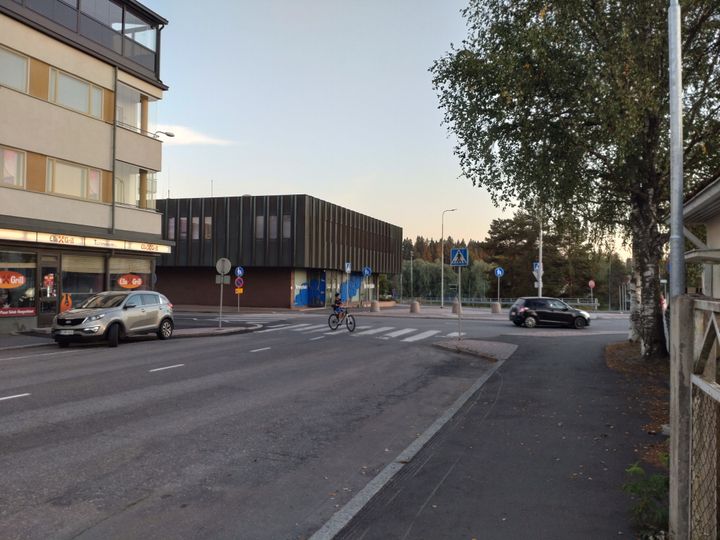 Kadunkulma kaupungissa, jossa autoja ja pyöräilijä suojatiellä.