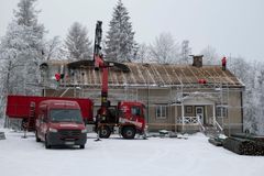 Talon kattoaa kunnostetaan, talon edessä nosturi ja pakettiauto, maassa lunta.