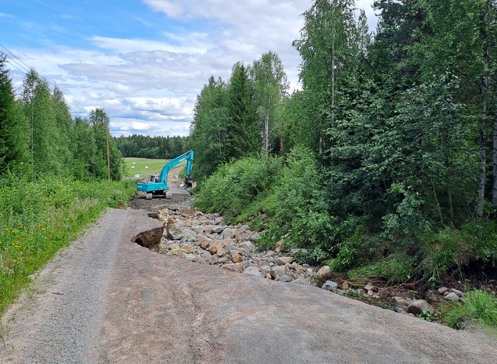 Multialla sijaitseva tie on sortunut noin sadan metrin matkalta. Kuvassa kaivinkone työskentelee alueella. Ympärillä metsää ja kivikkoa.