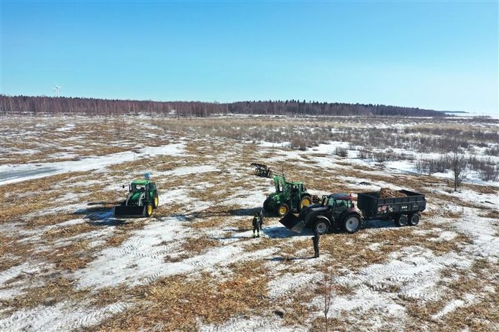 Raivattu saari kevättalvella, saarella traktoreita ja ihmisiä.