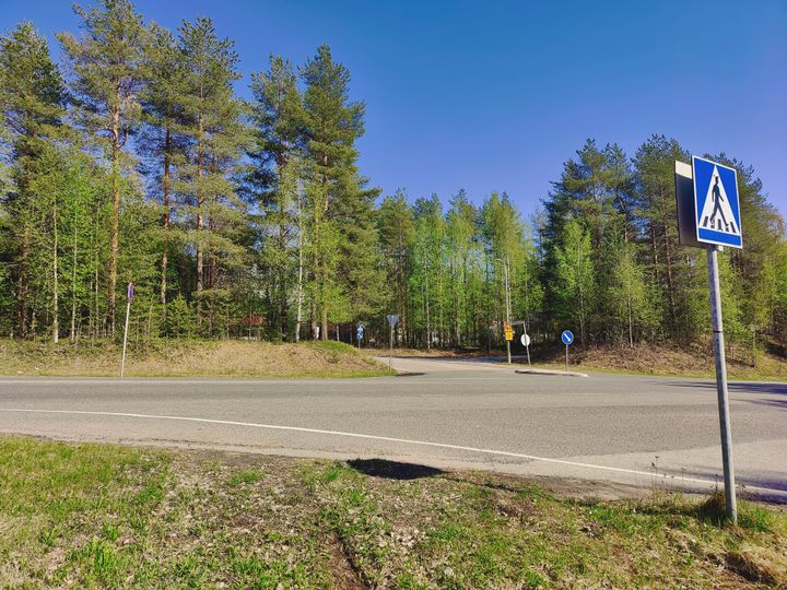 Risteysalue kuvattuna pyörätieltä, puita ja sininen taivas.