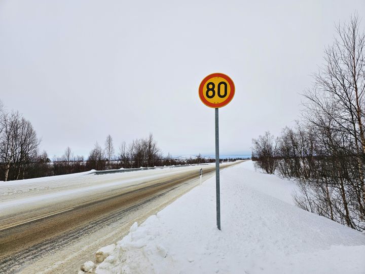 80 nopeusrajoituskyltti talvimaisemassa, taustalla tuntureita.
