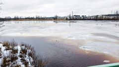 Kyrönjoella Isossakyrössä Kolkin sillan alapuolella jäät ovat paikoillaan. Sulaa vettä etualalla ja rakennuksia kaukana rantaviivassa.