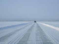 Talvinen näkymä: auto ajaa lumisella Hailuodon jäätiellä.