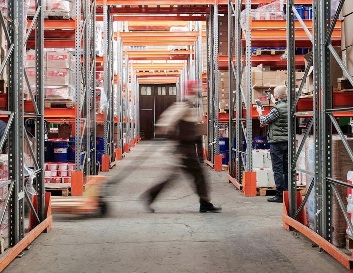 Varaston käytävillä työntekijöitä.