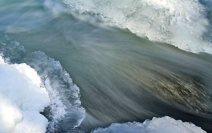 Virtaava koski, jossa on jäätä ympärillä.