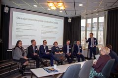 Ihmiset istuvat rivissä paneelikeskustelussa konferenssihuoneessa.