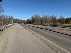 Risteyssilta, jossa on kaksi kaistaa. Molemmin puolin valaisinpylväitä ja ympärillä lehtipuita.