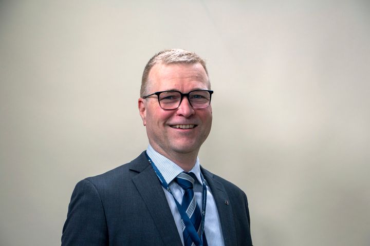 Valokuva%20henkil%F6st%E4%2C%20joka%20hymyilee%20ja%20on%20pukeutunut%20pukuun.