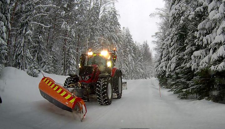 Aura-auto auraa lumen peittämää metsätietä talvimaisemassa.