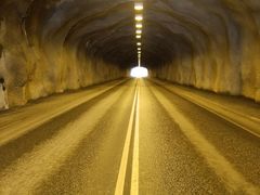 Alt text: Pitkä tunnelinäkymä, valot katossa ja tie keskellä.