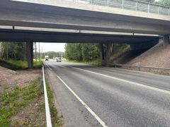 Silta maantien yli, taustalla metsä ja kulkevia autoja.