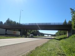 Silta, joka ylittää tien vehreässä ympäristössä. Taustalla näkyy autoja ja toinen silta.