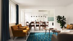 Havainnekuva kolmion alakerrasta: valoisa olohuone ja ruokailutila, jossa on moderni sisustus.