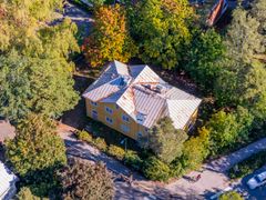 Ilmakuva keltaisesta talosta vehreän ympäristön keskellä.