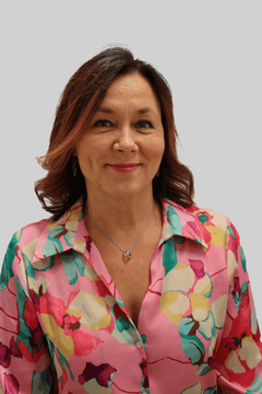 Hymyilevä nainen yllään värikäs paitapusero.