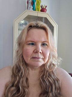 Lähikuvassa nainen, jolla on vaaleat, pitkät, hieman kiharat hiukset.