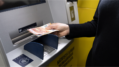 Henkilö nostaa seteleitä pankkiautomaatista.