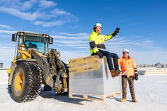 Kuvassa kaksi miestä työpukineissa. Toinen istuu kuorman päällä ja toinen seisoo. Miehet hymyilevät tyytyväisinä.