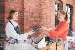 Kaksi henkilöä tekemässä maksutapahtumaa, toinen heistä ojentaa maksukortin lukijalaitteen päälle.