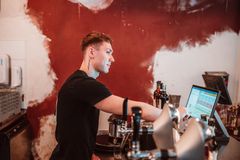 Nuori mies työskentelee kahvilassa ja näppäilee Restolution-kassajärjestelmää.