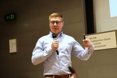 Mies puhuu mikrofoni kädessä