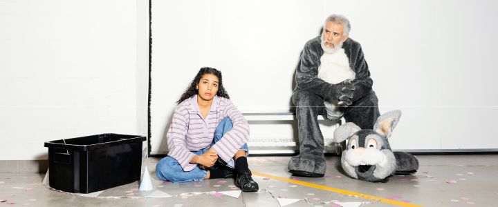 Skådespelarna Antonia Atarah och Elihú Galván sitter på golvet mitt i scenografin. Galván är klädd i en grå djurkostym.