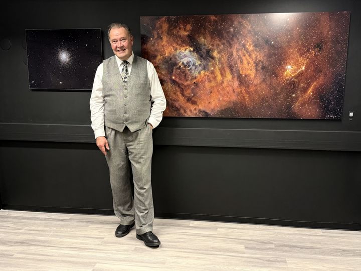 J-P Metsävainio seisoo seinälle ripustettujen avaruusvalokuvien edessä.