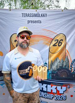 Terassimölkky ry:n Vesa seisoo MM-kisojen mainoslakanan edessä ja pitää kädessään luvun 512 muodostavia Mölkky-keiloja.