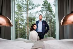Katja ja Ilkka Länkinen Arctic TreeHouse Hotelin sviitin suuren maisemaikkunan edessä.