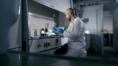 Tutkija työskentelee valkoisessa takissa laboratoriossa.