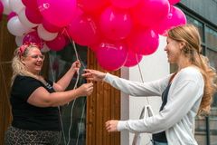 Kaksi naista hymyilee ja pitelee TampereMission pinkkejä ilmapalloja.