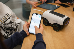 Lapsi ohjaa Bella-robottia älypuhelinsovelluksella pöydän ääressä.
